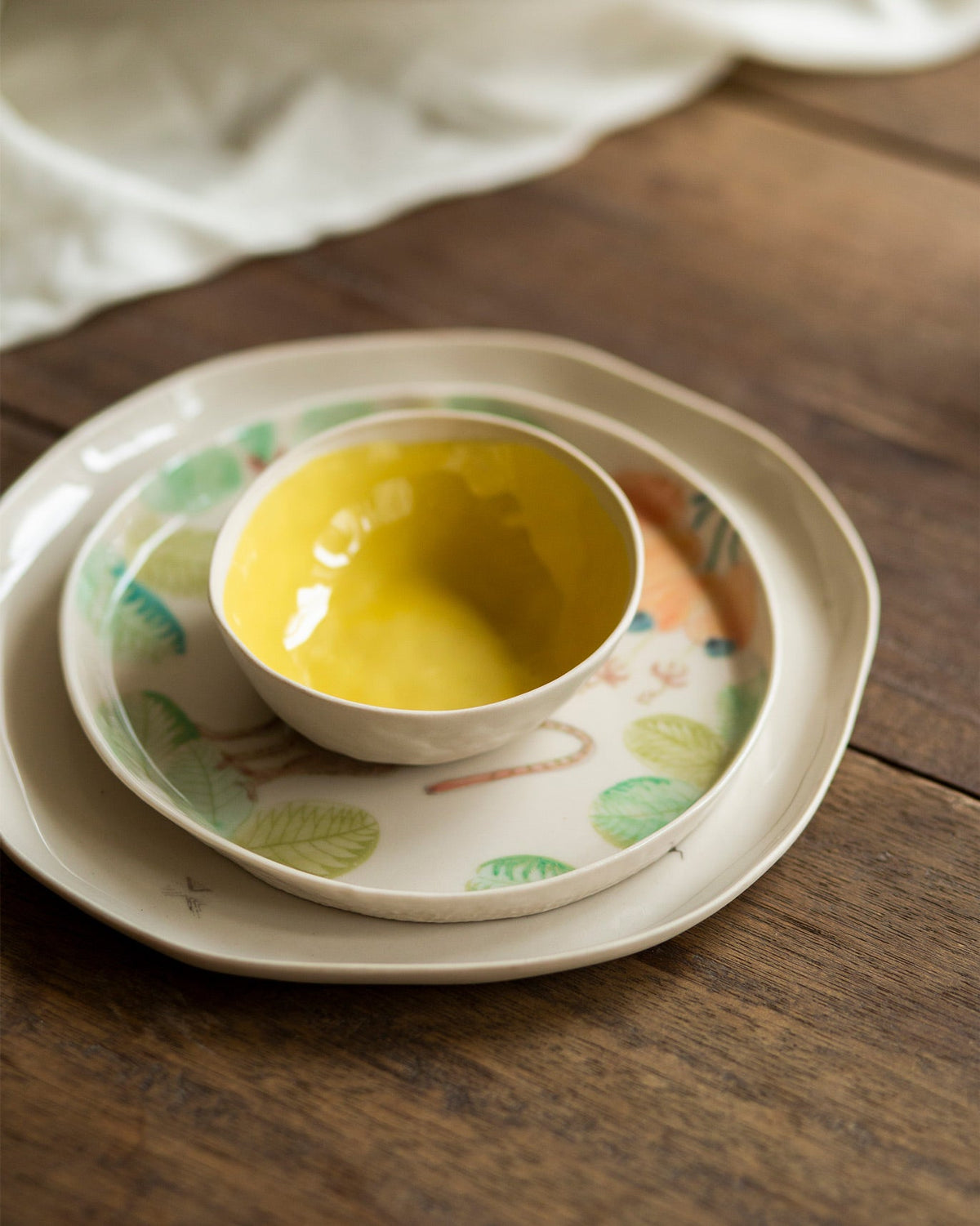 Mandovi Katori with a yellow glaze, sitting on a patterned plate.