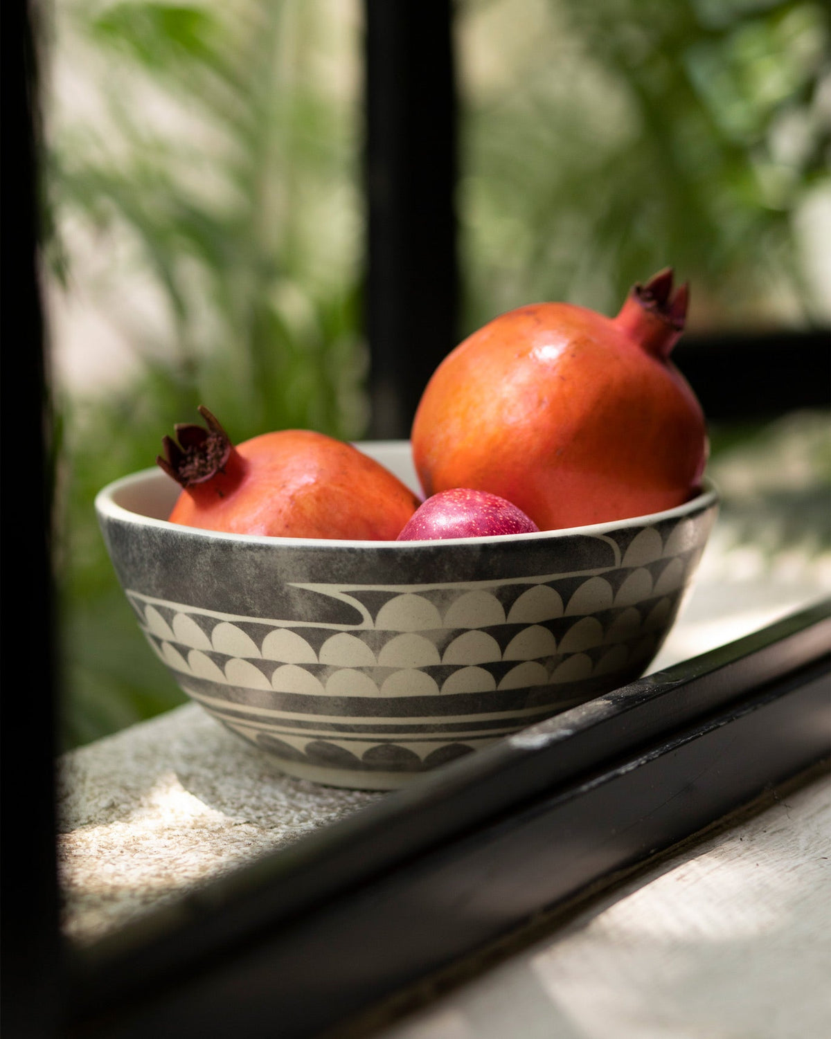 Aasma Curry Bowl holding two pomegranates.