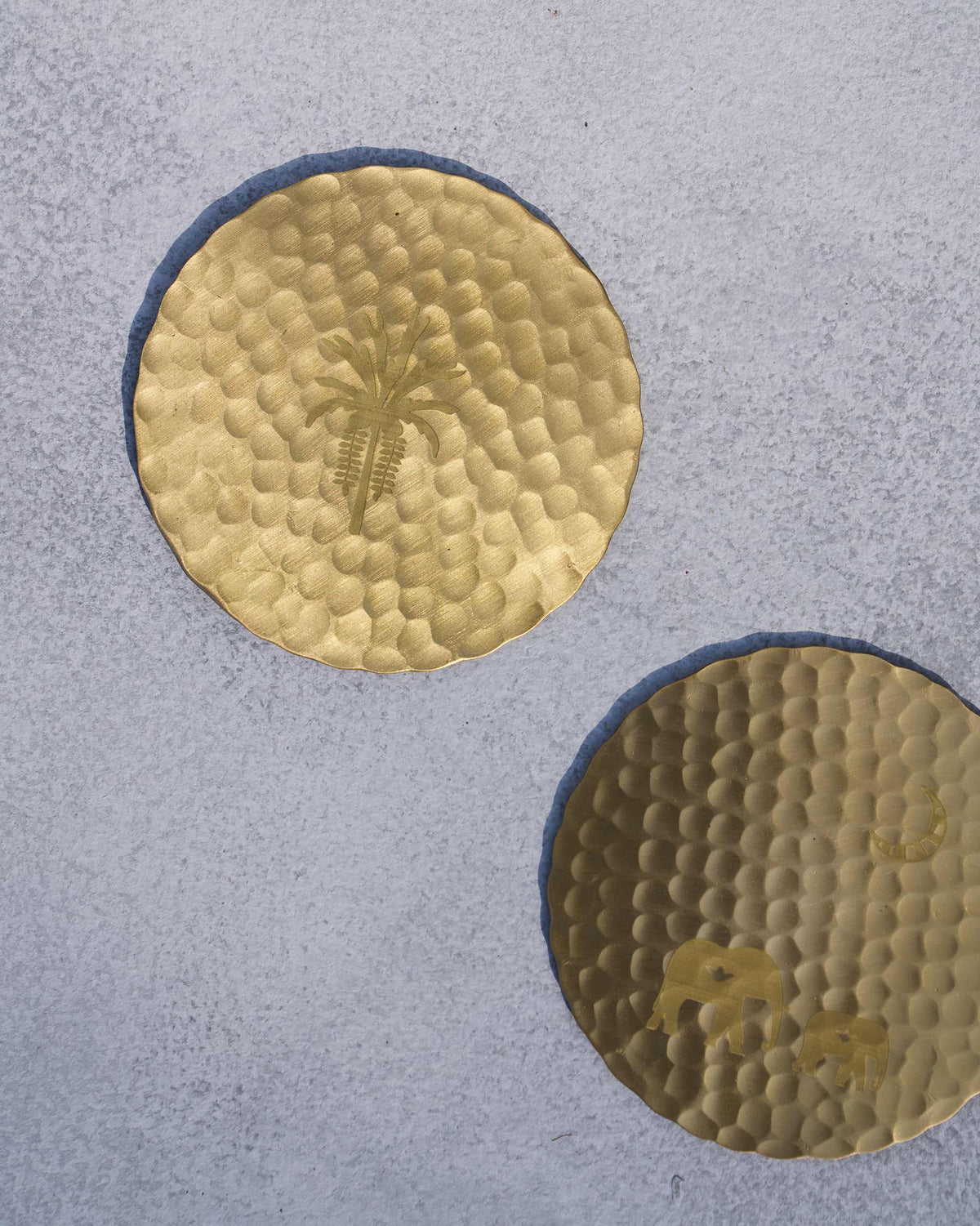 Hammered gold Palm Grove coasters with palm tree and elephant motifs.
