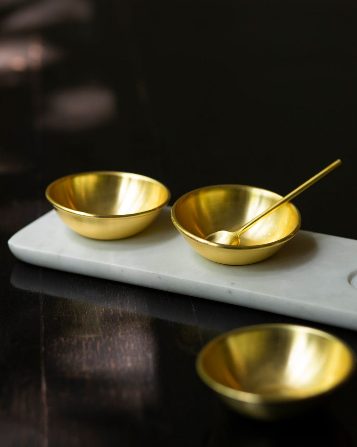 Side view of the Dariya Tray Set with brass bowls on a marble tray.