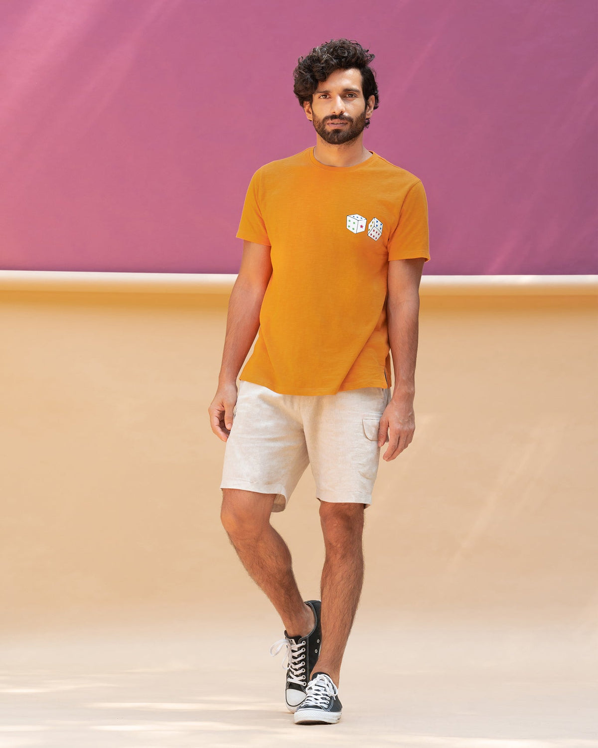 Full-length view of an orange Roll the Dice t-shirt worn by a person.