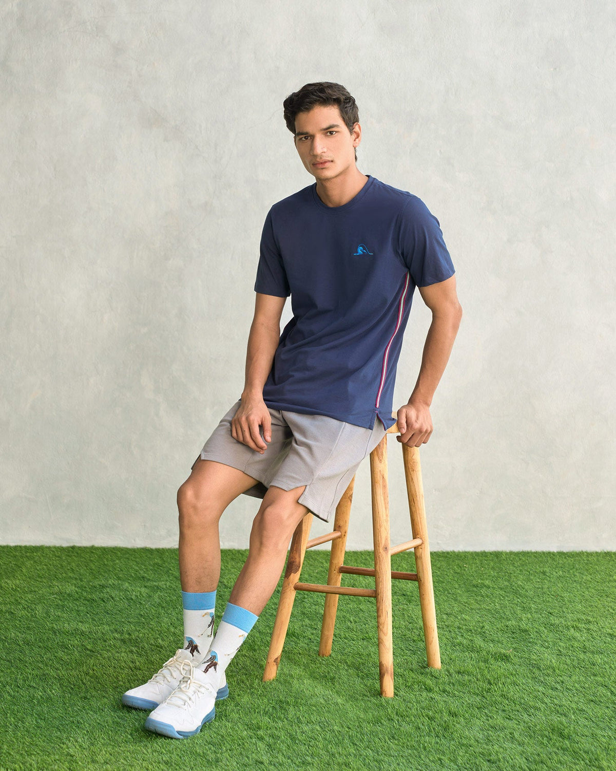 Full-length view of a navy Club Crew Neck T-shirt worn by a seated person.