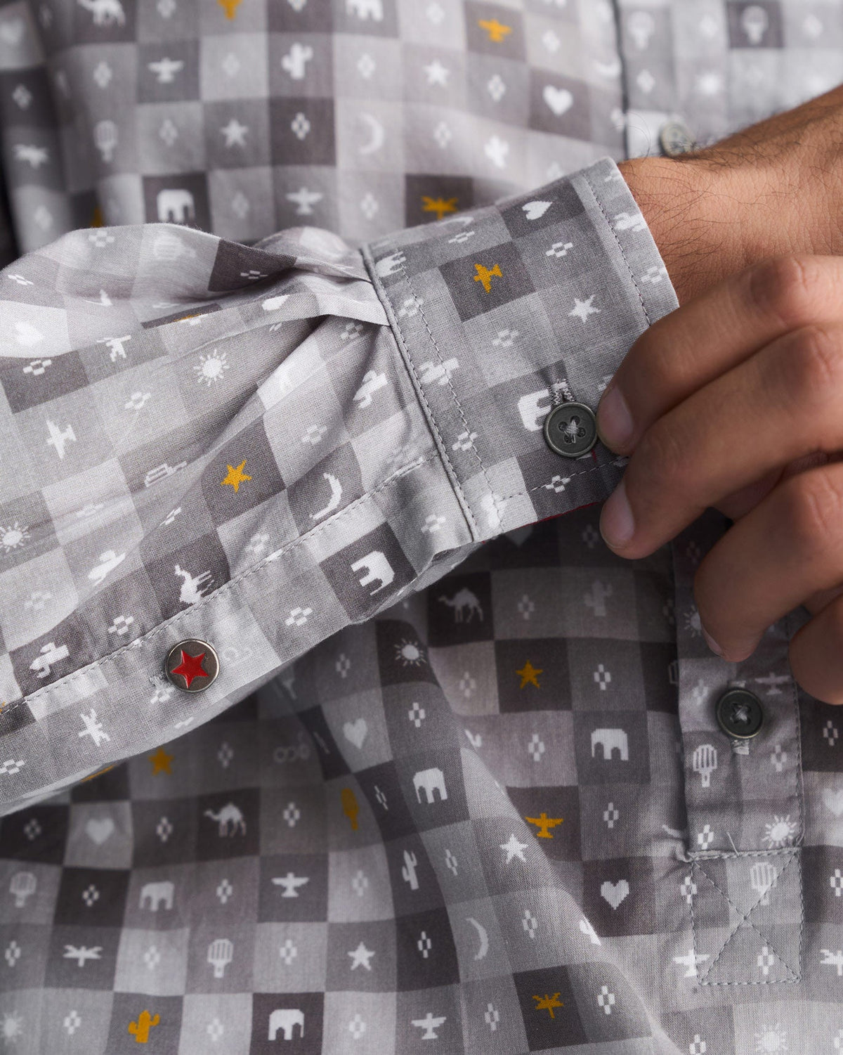 Close-up of a grey Pocket Shirt cuff with a red star button.