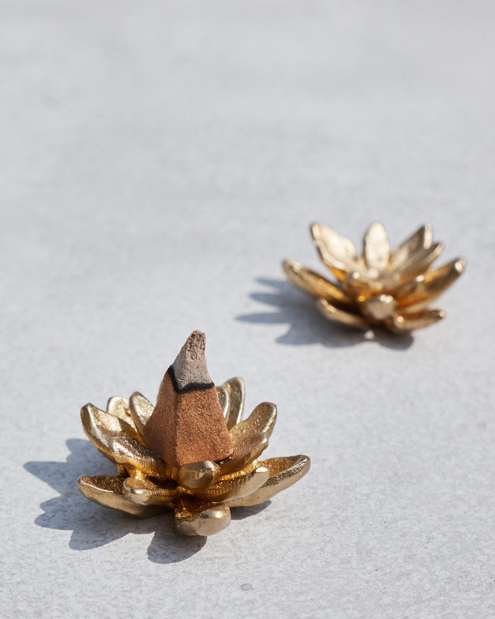 Pair of Kamal gold lotus incense holders with a lit incense cone.