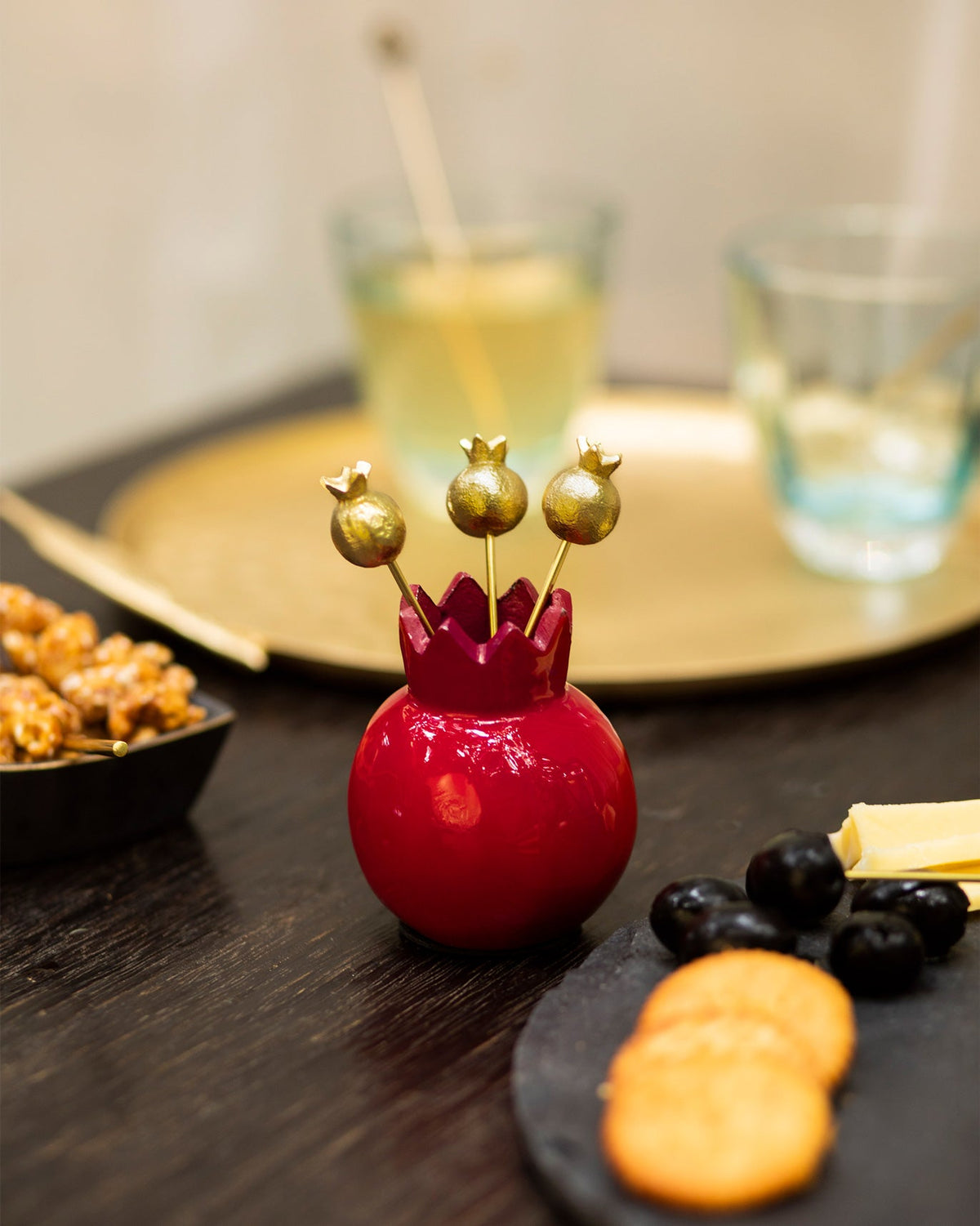 Anar Kebab Picks in a red pomegranate-shaped holder on a dark table.