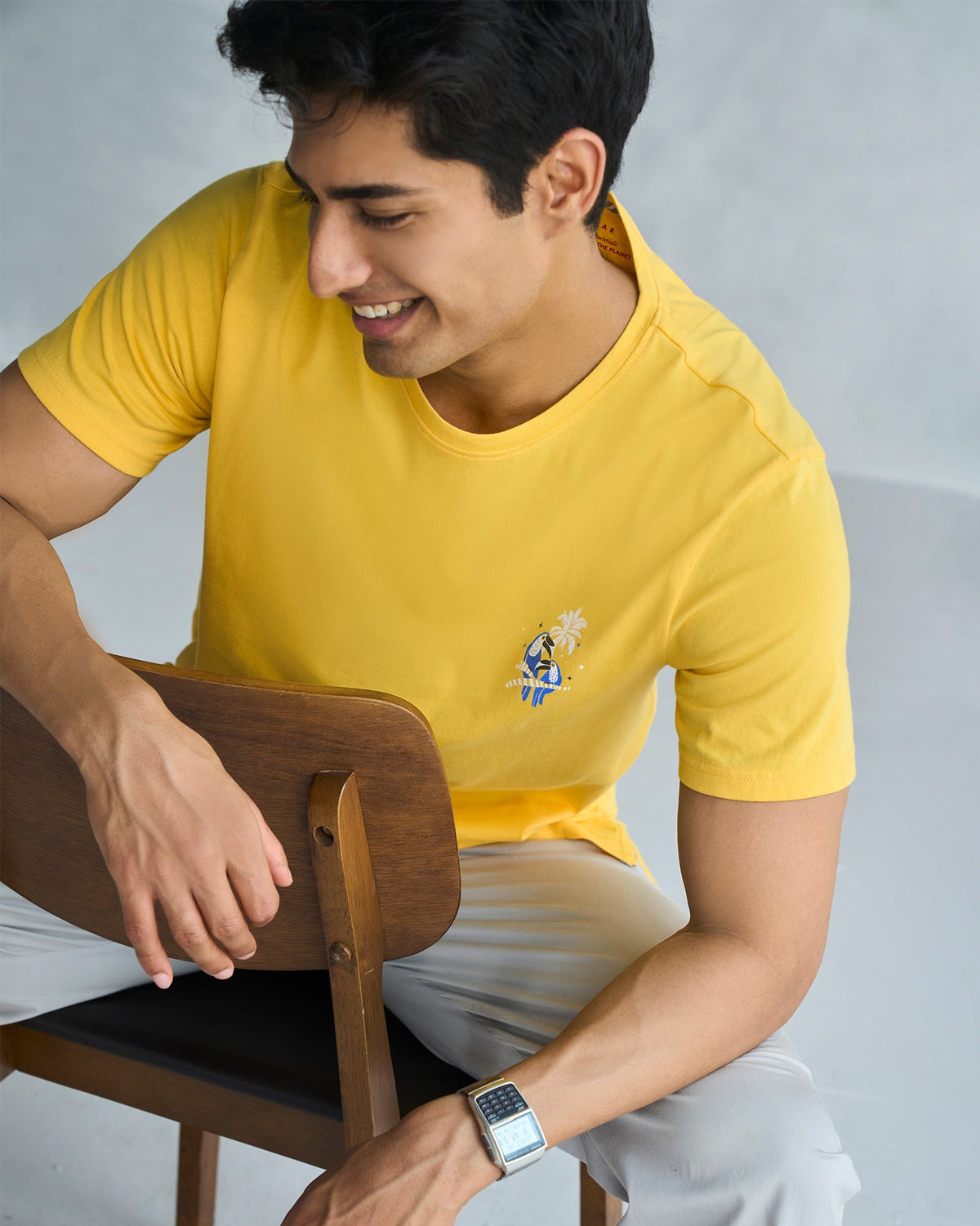 Three-quarter view of a yellow Toucan T-shirt worn by a seated person.