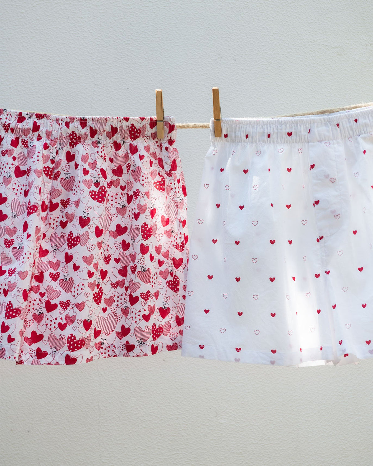 Big Hearts Puppies Boxers with a red all-over heart print, hung on a line.