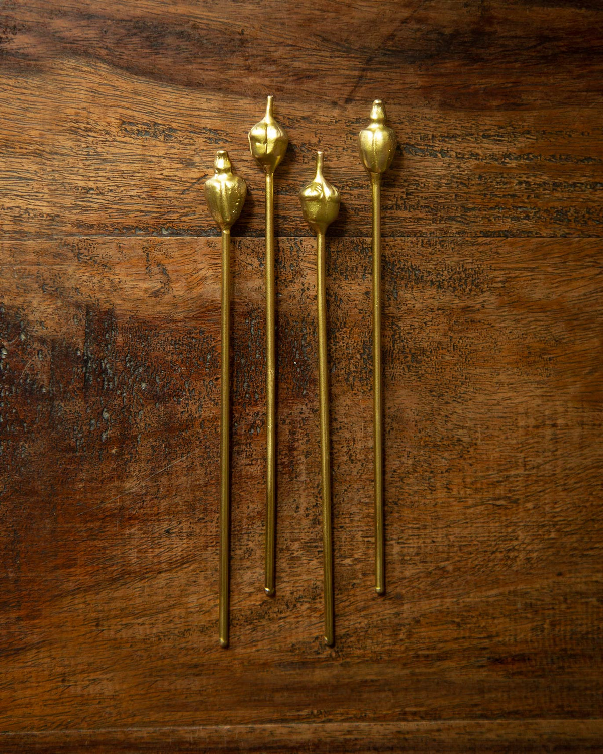 Set of four Cashew and Kokam Stirrers laid flat on a wooden table.