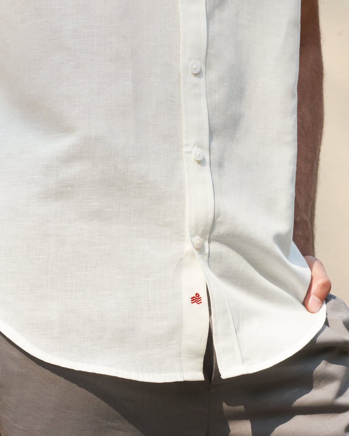 Close-up of the hem of a Half Sleeve Shirt showing a small red embroidered mark.