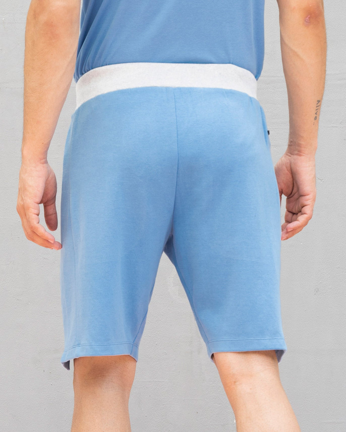 Back of blue Rally training shorts worn by a person.