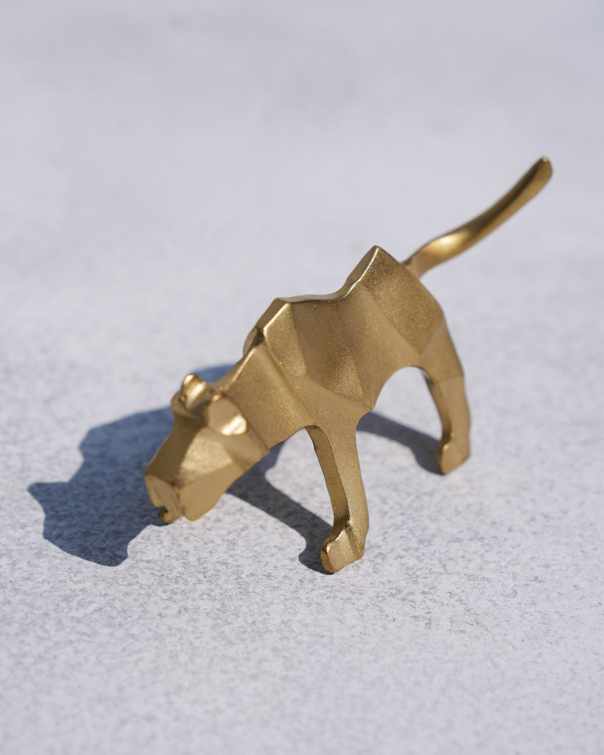 Gold leopard origami with its head lowered, seen at a three-quarter angle.