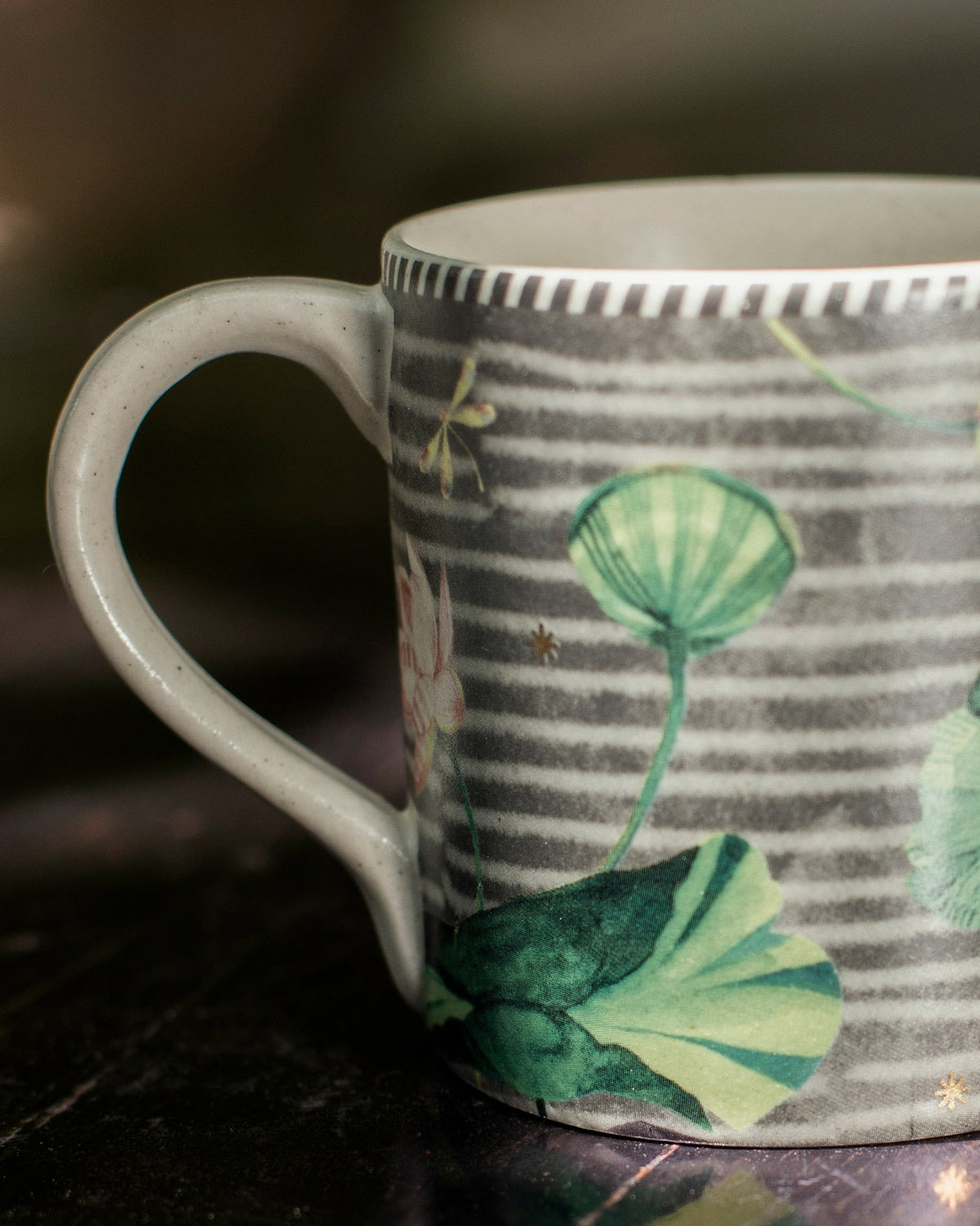 Side view of a Kamal mug with a cream handle and green leaf prints.