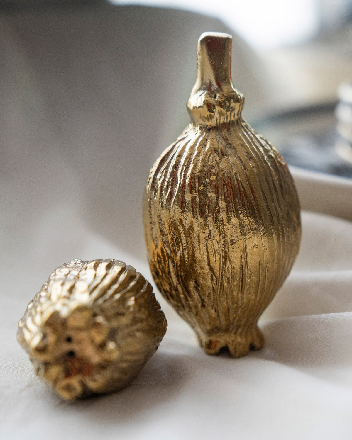 Poppy Salt & Pepper Shaker in gold standing beside a second one on its side.
