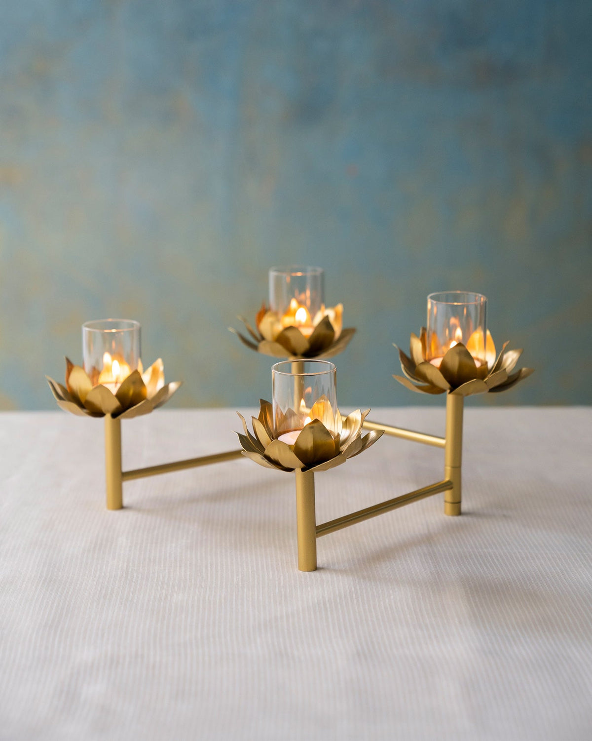Sitara tealight stand with four lit holders on a white table.