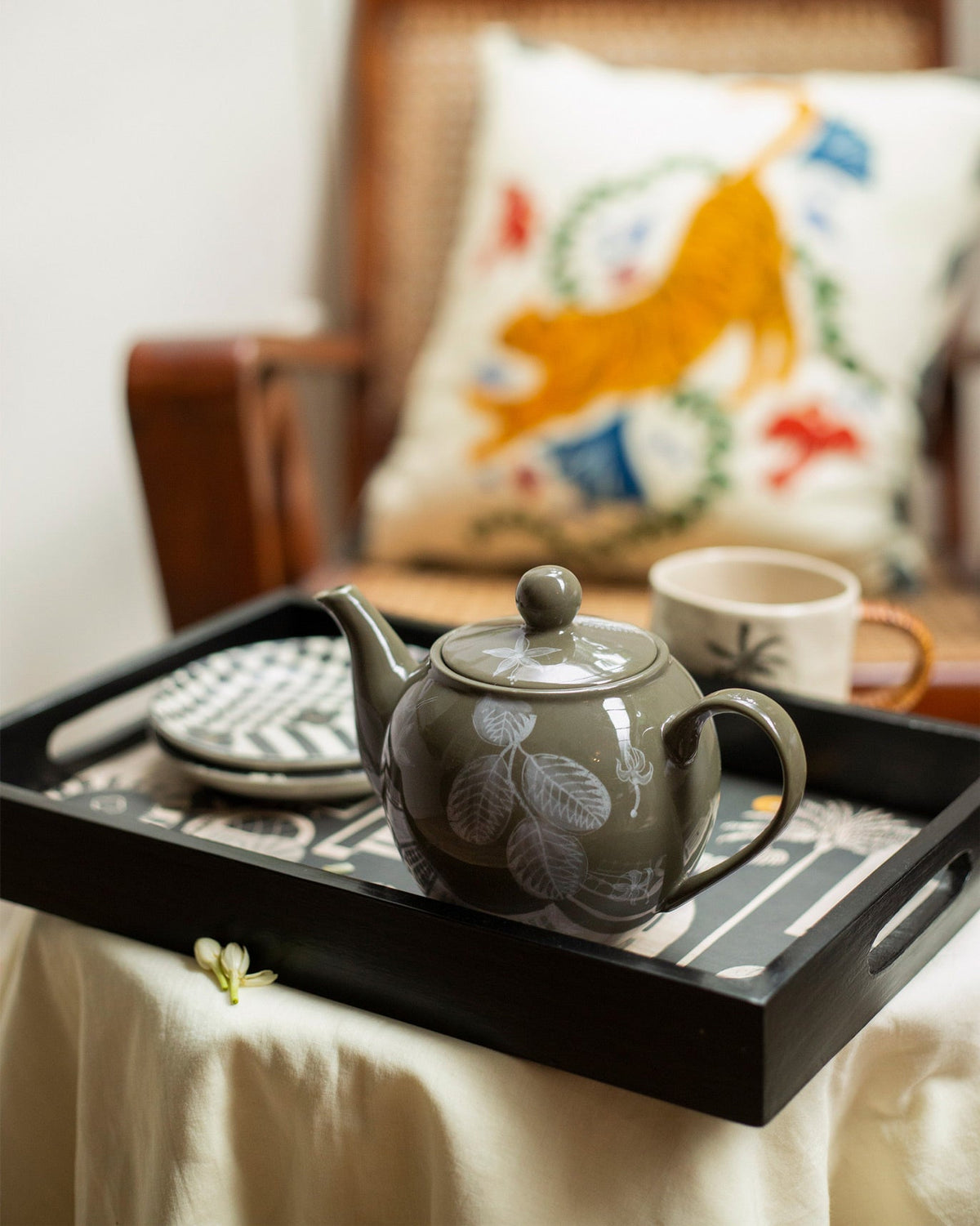 Mandovi Teapot on a tray, its olive-green body decorated with white leaves.