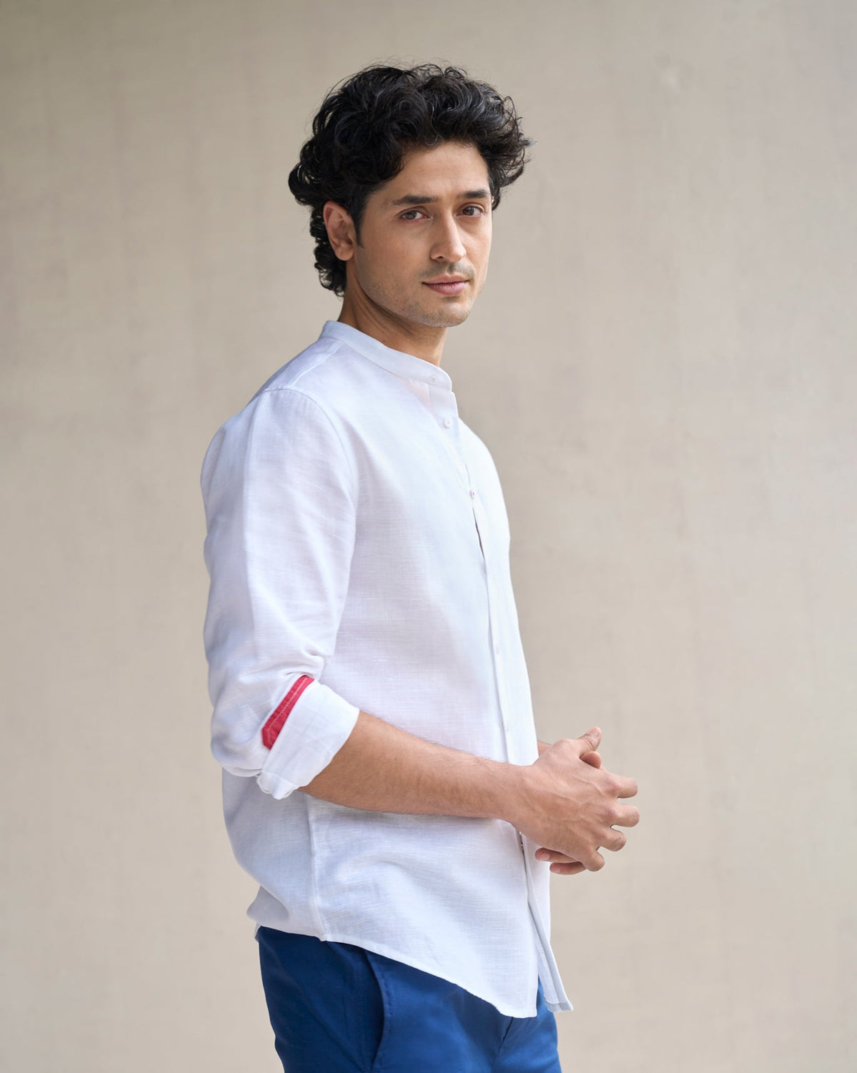 Person in a white Nawab shirt with a red cuff lining, turned to the side.