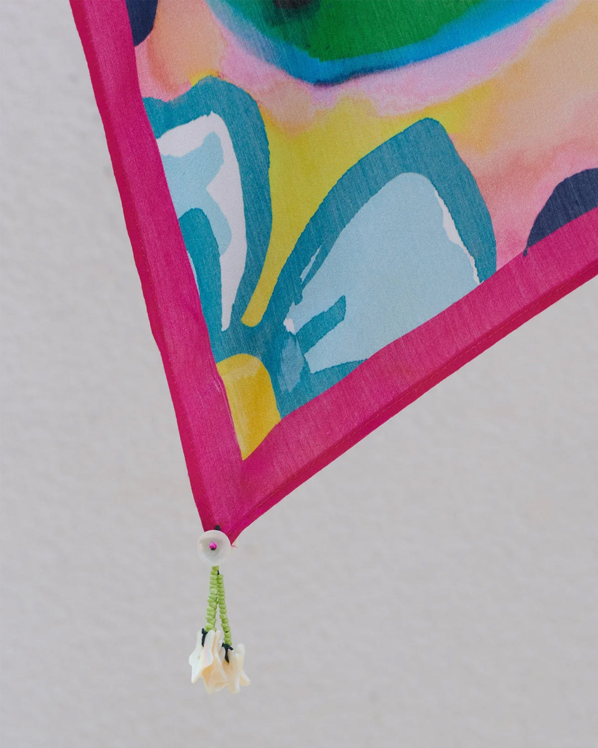 Close-up of a Meadow scarf corner showing blue petals, a pink edge and a white flower tassel.