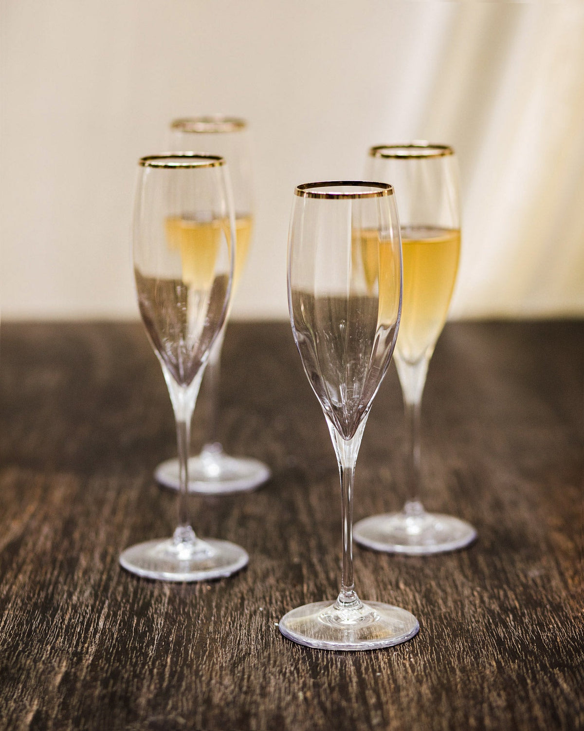 Four Marina Champagne Flutes with gold rims, one empty in front.