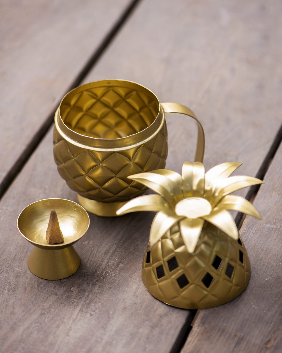 Ananas dhuna with its lid removed, beside an incense cone holder.