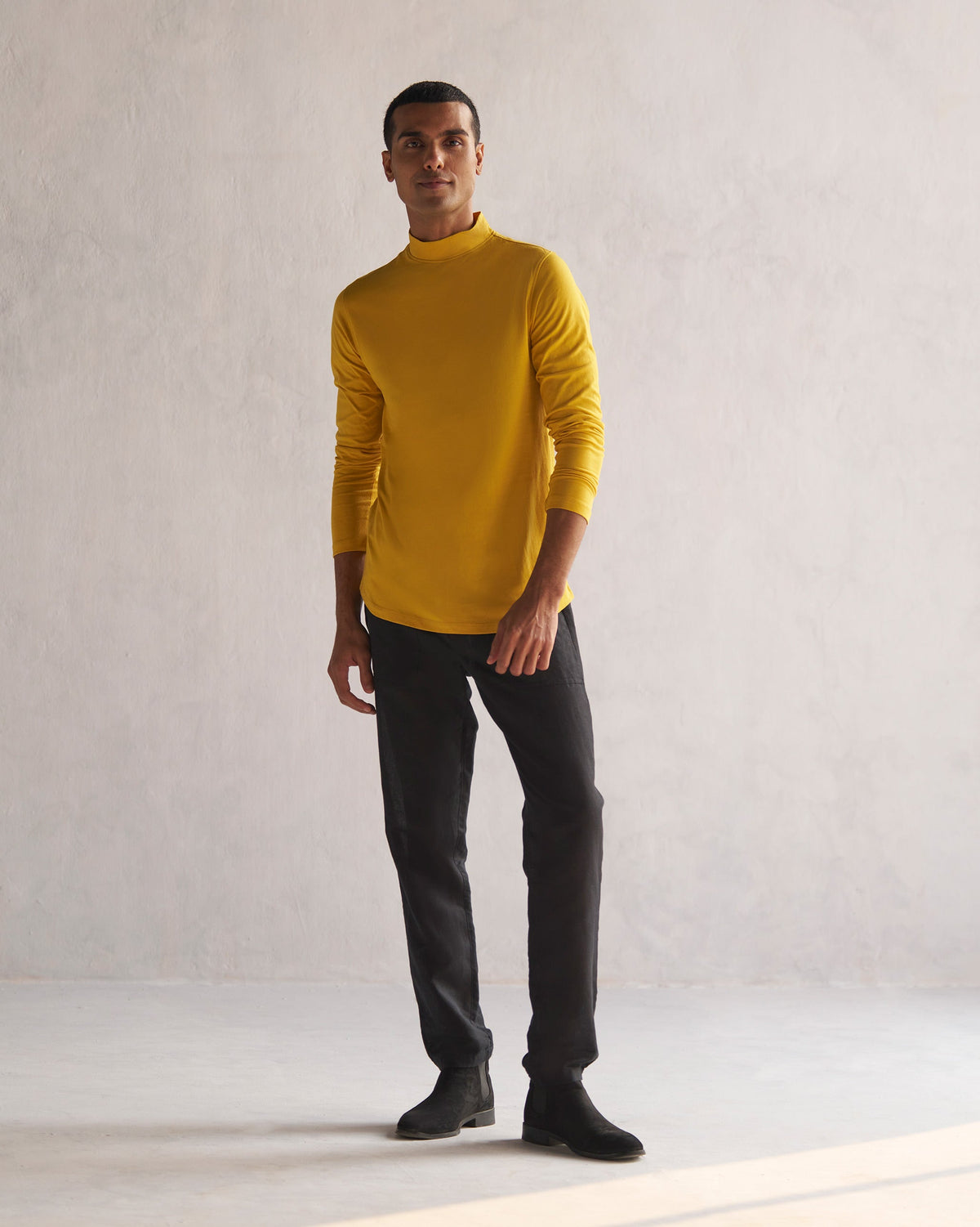 Full-length view of a mustard turtle neck t-shirt worn by a person.