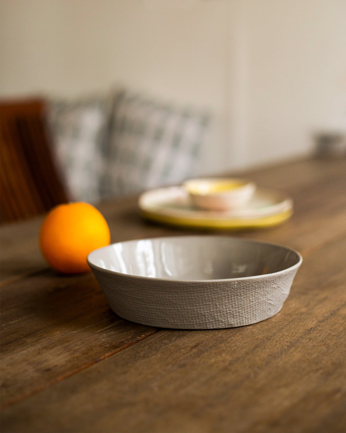 Side view of the Mhadei serving bowl in soft grey with a textured outer wall.