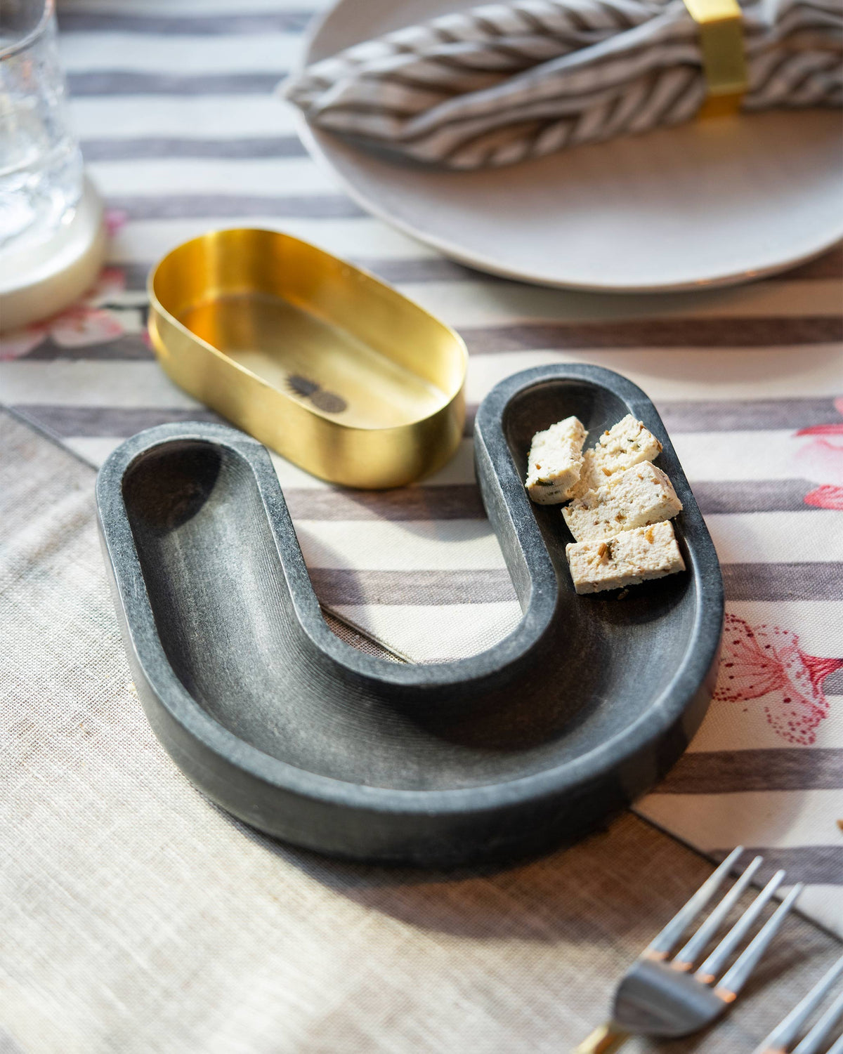 Ananas tikka tray with bite-sized pieces on it, beside a gold pineapple dish.