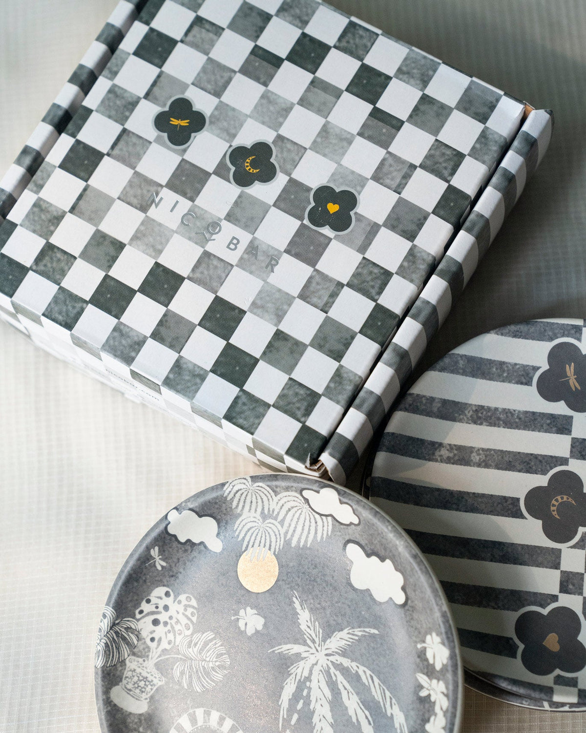Nicobar box with a checkerboard pattern, shown beside Mandovi Tea Plates.