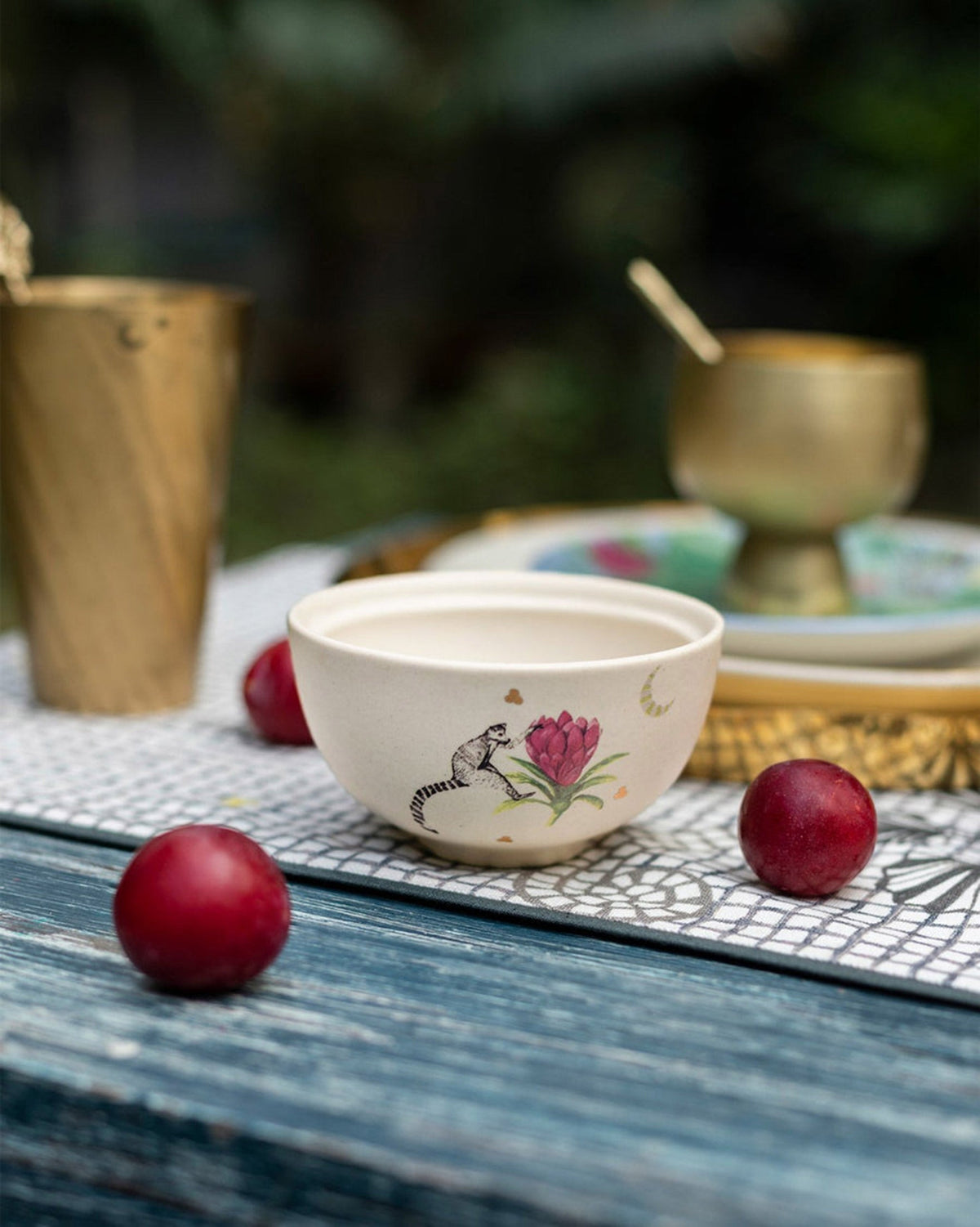 Cream Lemur katori with lemur and flower motif on a table runner.