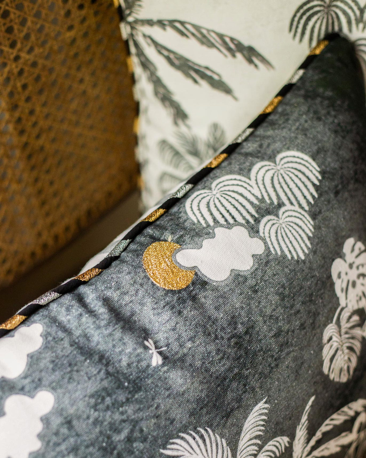 Close-up of a Coastal Evening Cushion Cover showing a gold moon, clouds and palm fronds.