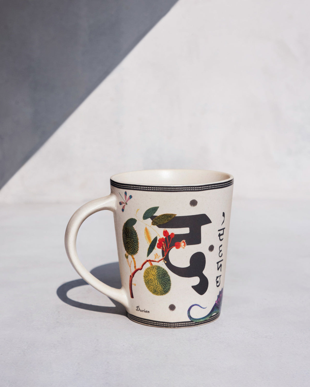 Cream Dariya mug with Devanagari script, a Durian motif, and red berries.