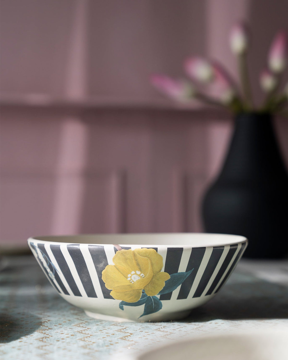 Side of a Myra curry bowl with charcoal stripes and a yellow flower.