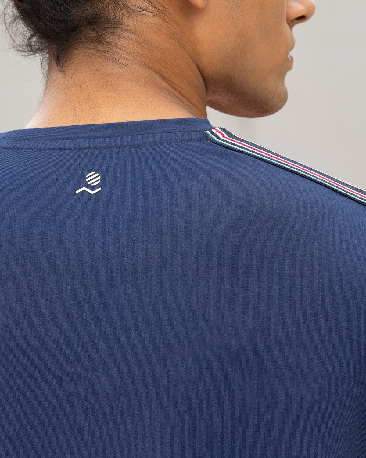 Close-up of the back neckline of a navy Nico crew neck t-shirt with a small white logo.