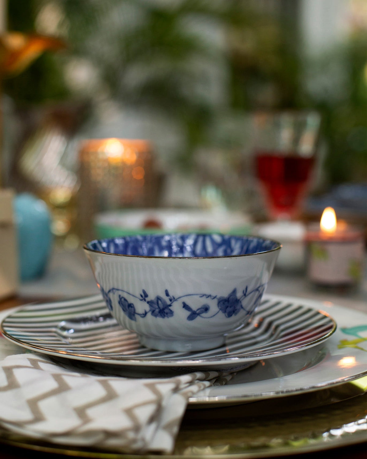 Aika Katori bowl with blue floral motifs on its sides, set on a striped plate.