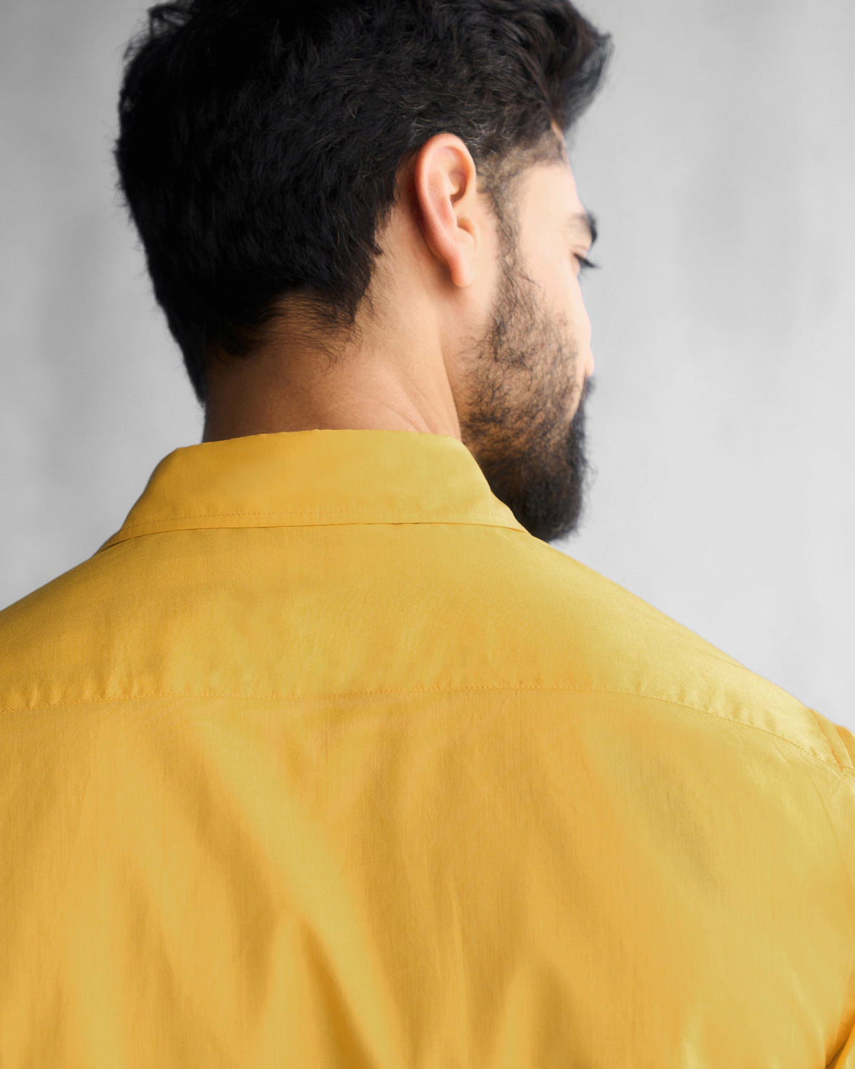 Close-up of the back collar of an ochre Half Sleeve Shirt worn by a person.