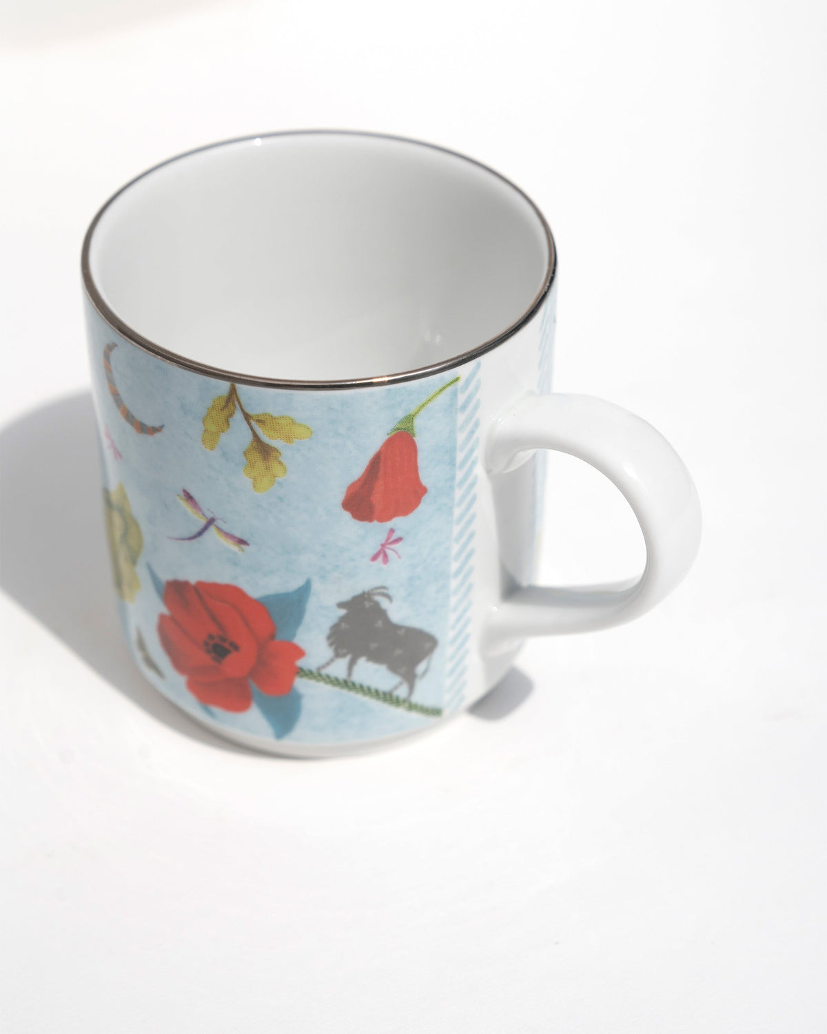 Overhead view of the Wildflower Mug showing a red poppy and a dragonfly.