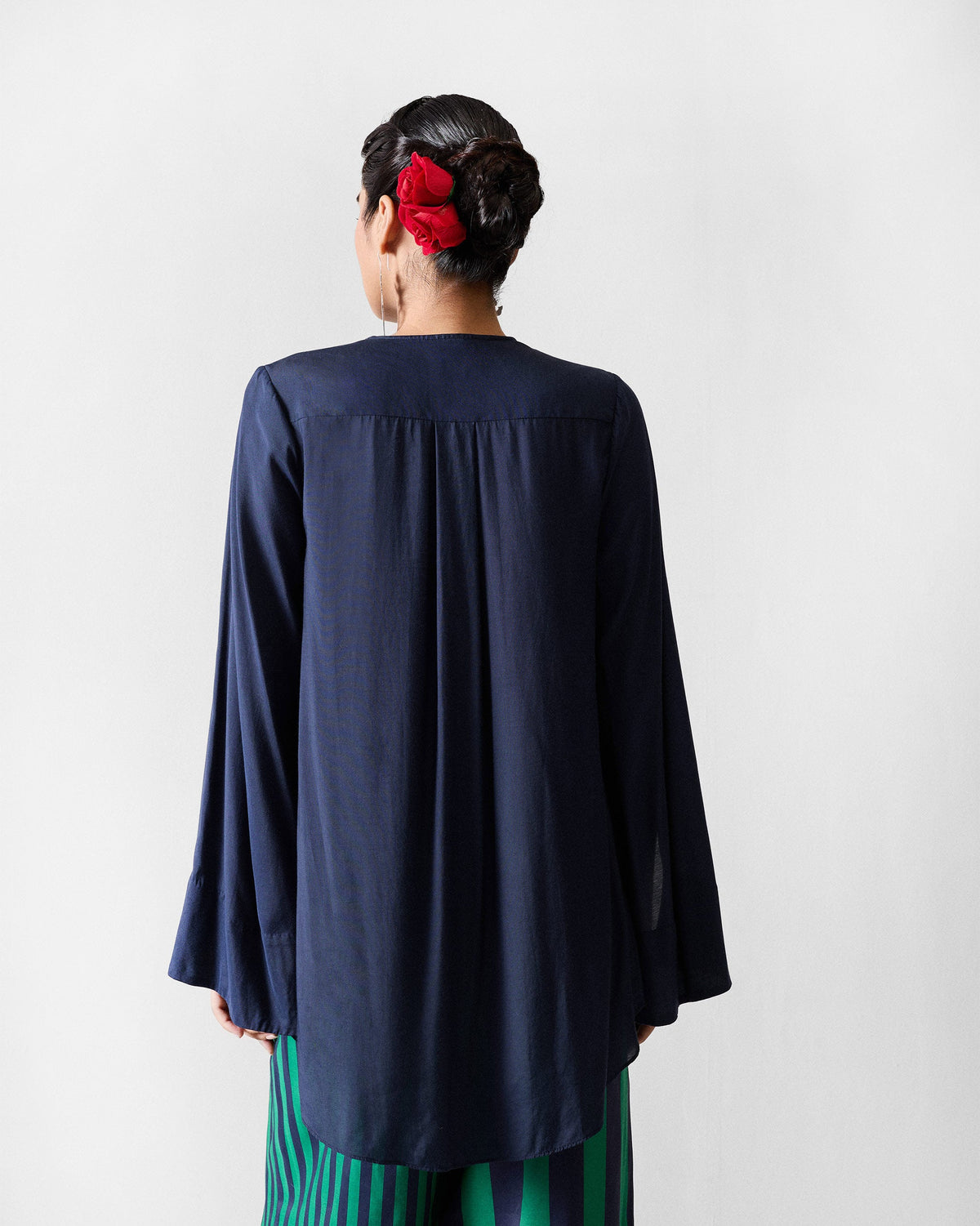 Back of a navy Panaji top with a pleated yoke over striped pants.