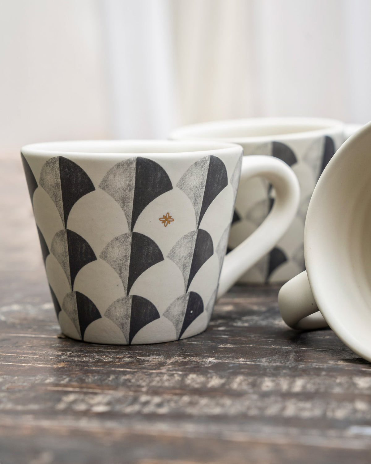 Close-up of a Khardung mug with charcoal scallop pattern and gold accent.