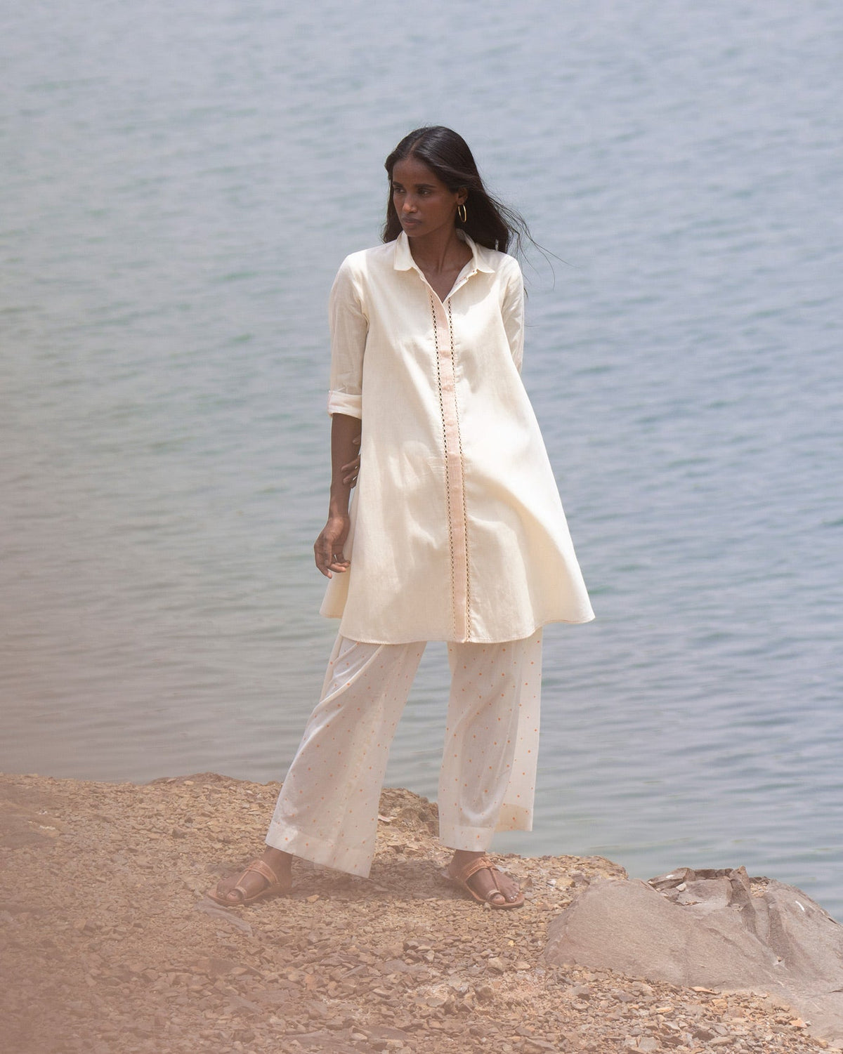 Person wearing an ivory Back Flayer Top with sleeves rolled to the elbow.