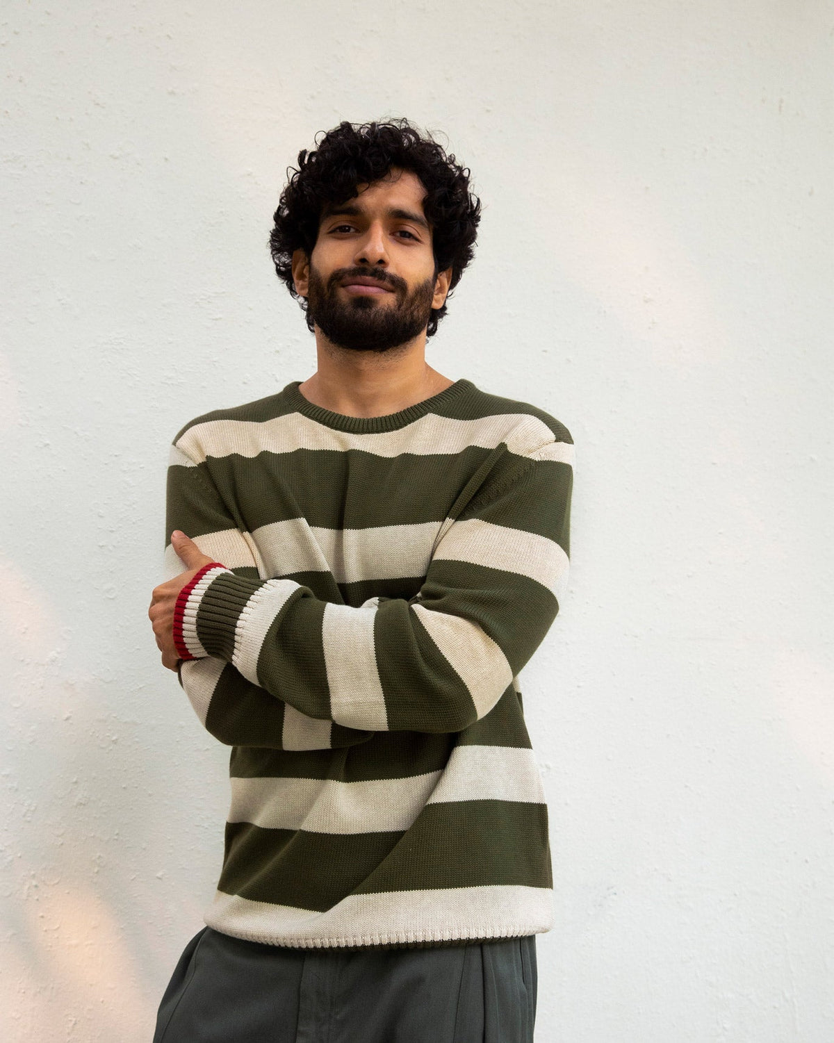 Person with arms crossed wearing a striped olive and oatmeal Round Neck Sweater.
