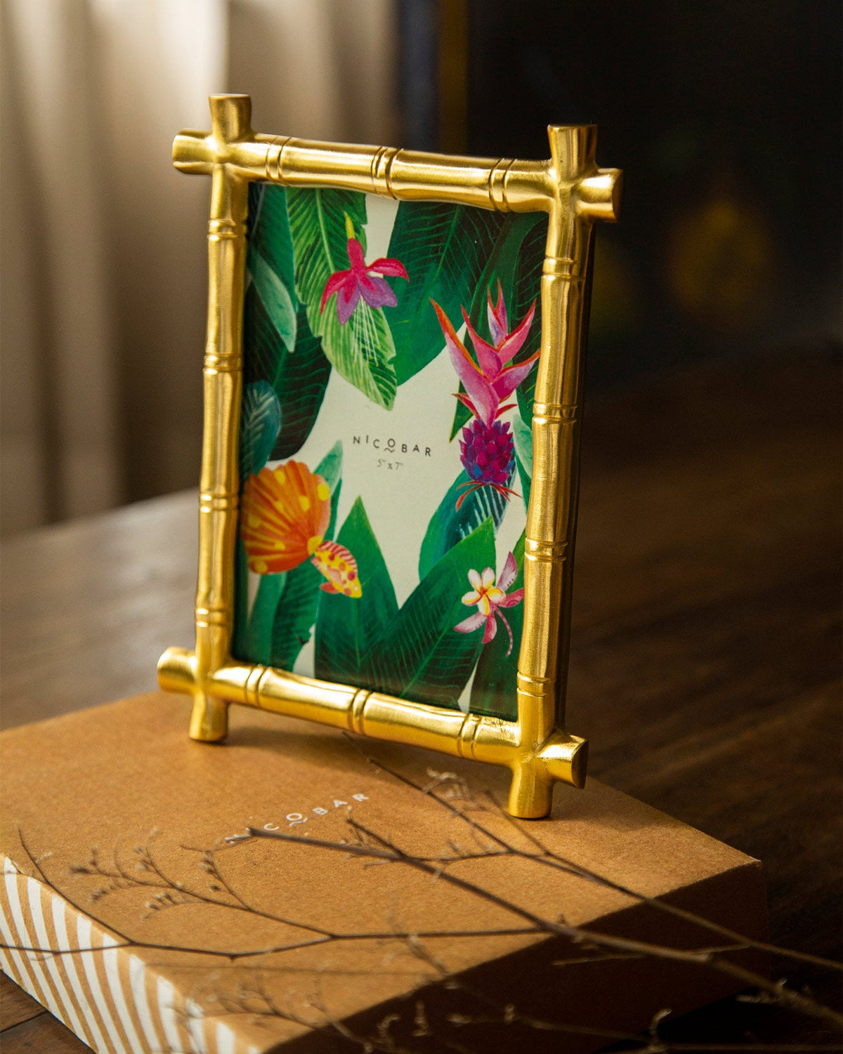 Gold bamboo photo frame standing on a Nicobar gift box.