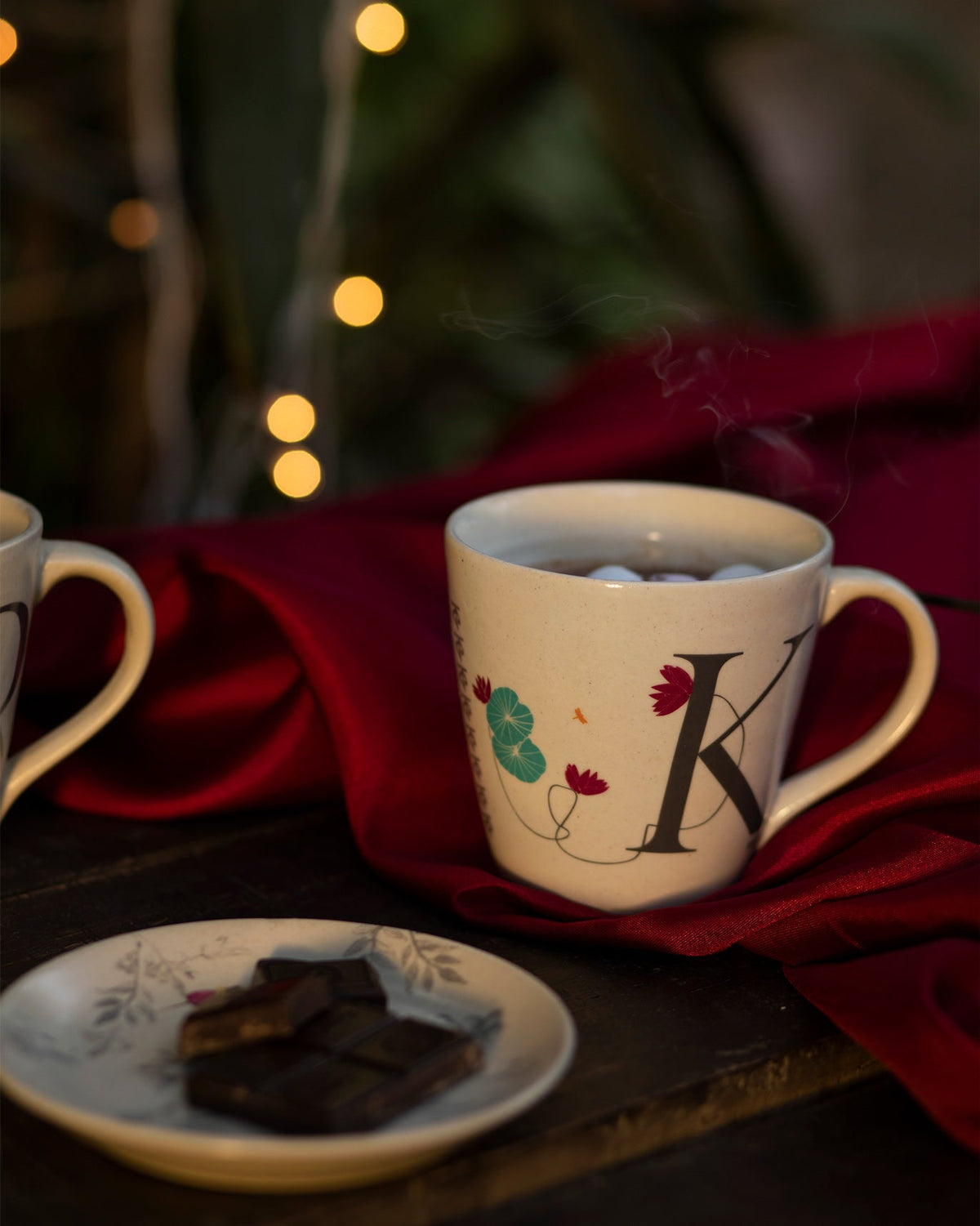 Alphabet K Mug on red fabric, showing its large K and flower print.