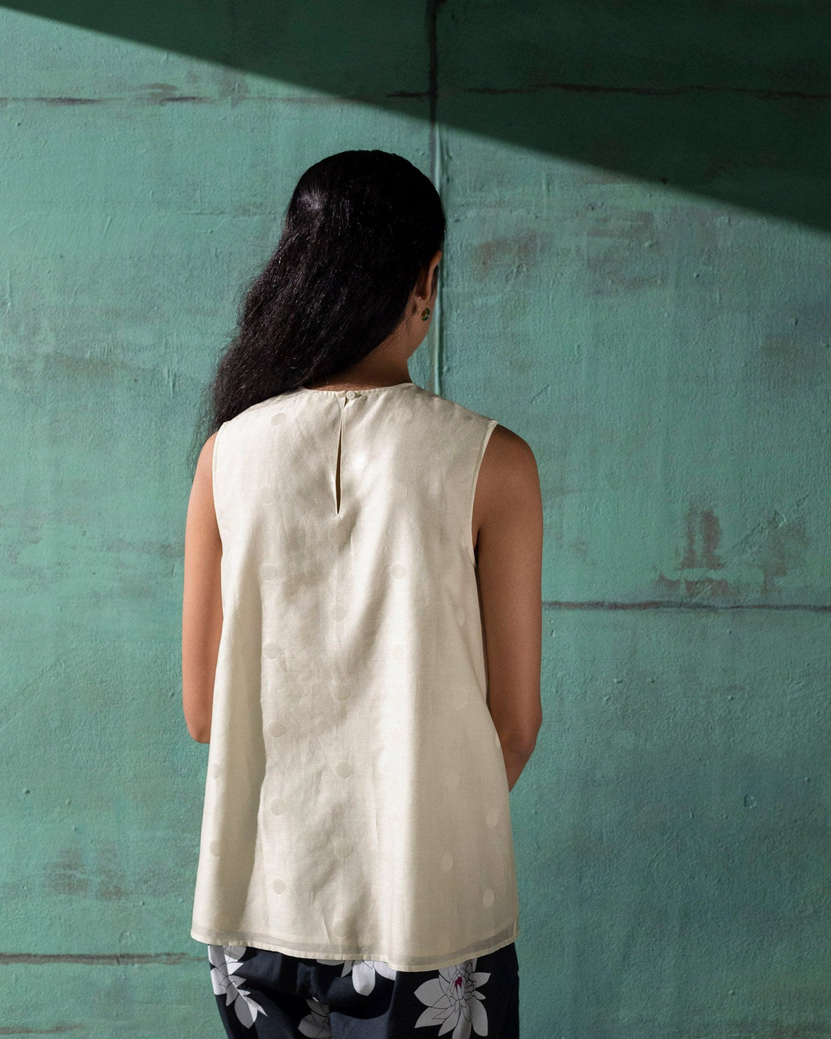 Back of an ivory sleeveless A-line top with a small keyhole at the nape.