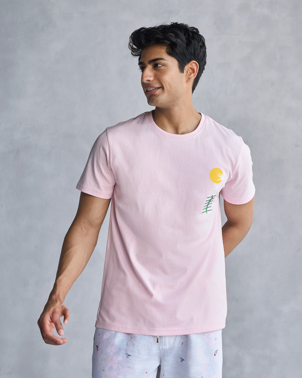 Person wearing a soft pink See Ya Later Alligator t-shirt with a yellow sun print on the chest.