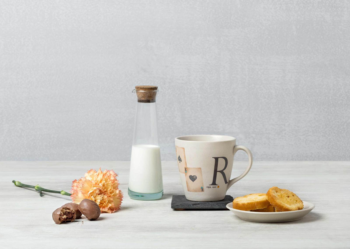Alphabet R Mug with a large R and a small heart motif, set on a table.