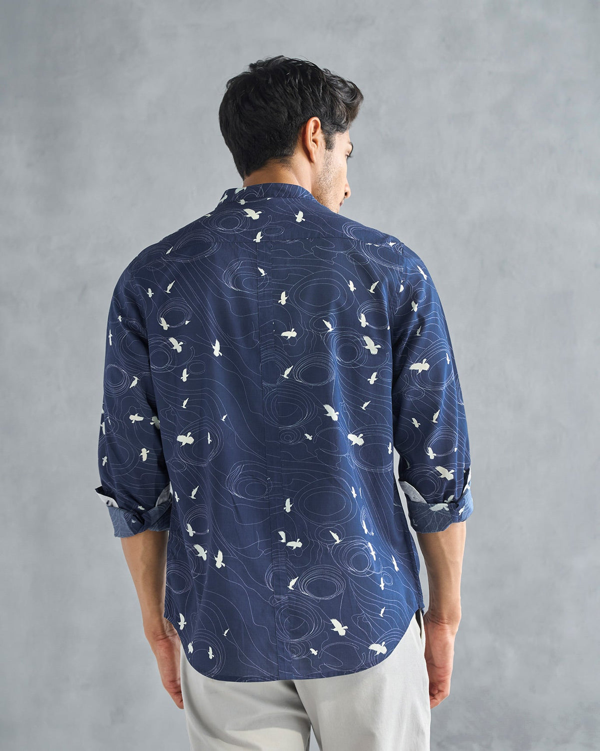 Back of a deep navy Nawab shirt with a white bird print, worn by a person.