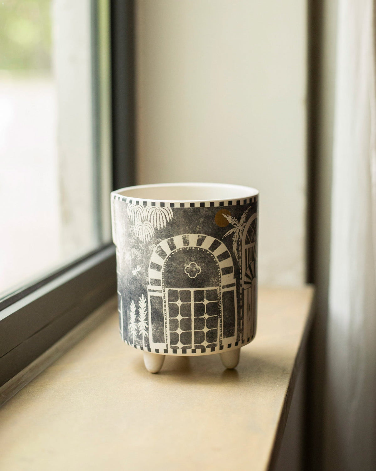 Monochrome planter with arched doorway print on a wooden windowsill.
