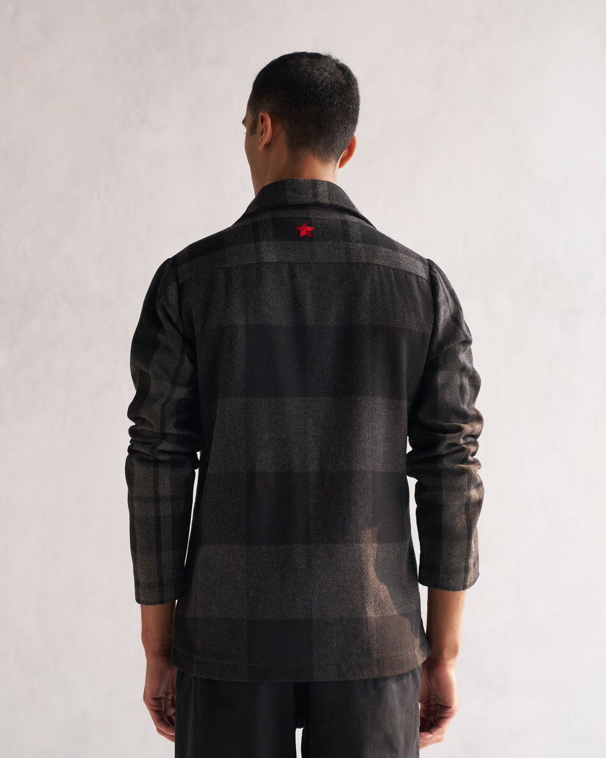 Back of a black and grey checked Woollen Knotch Collar Jacket worn by a person, with a red star at the upper back.