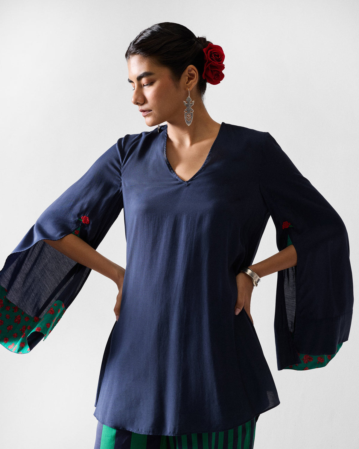 Person wearing a navy Panaji top with flared slit sleeves and green lining.