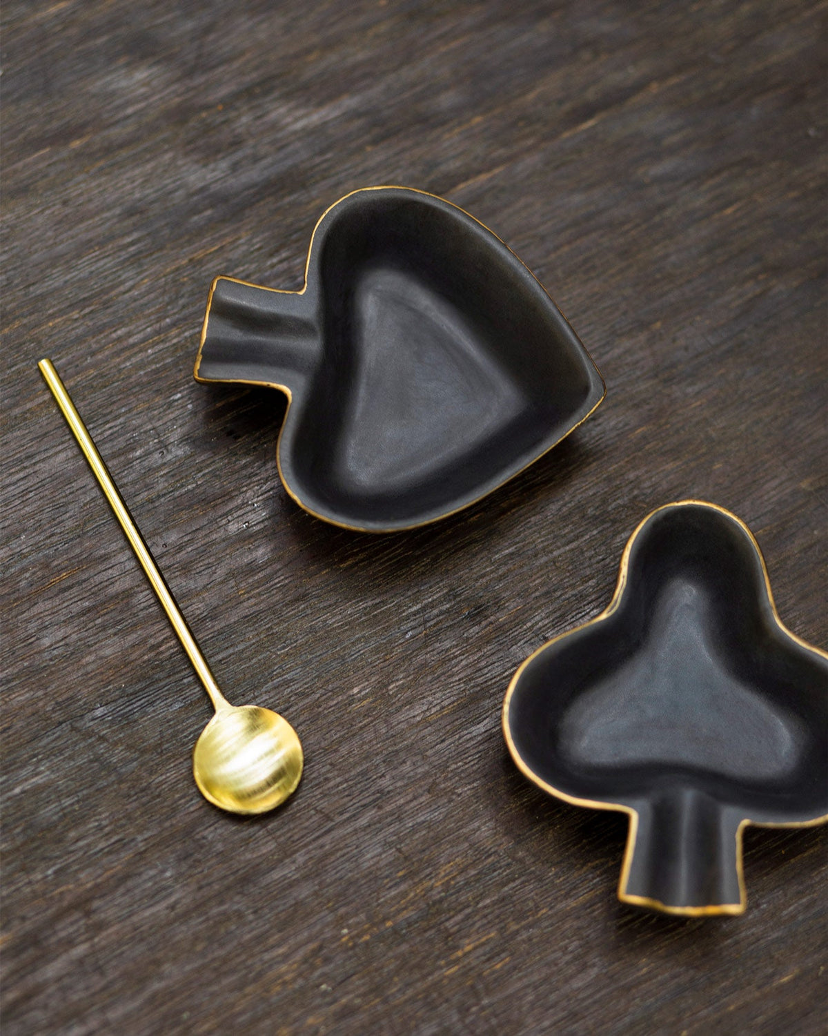 Top-down view of the spade and club trinket dishes with a gold spoon.