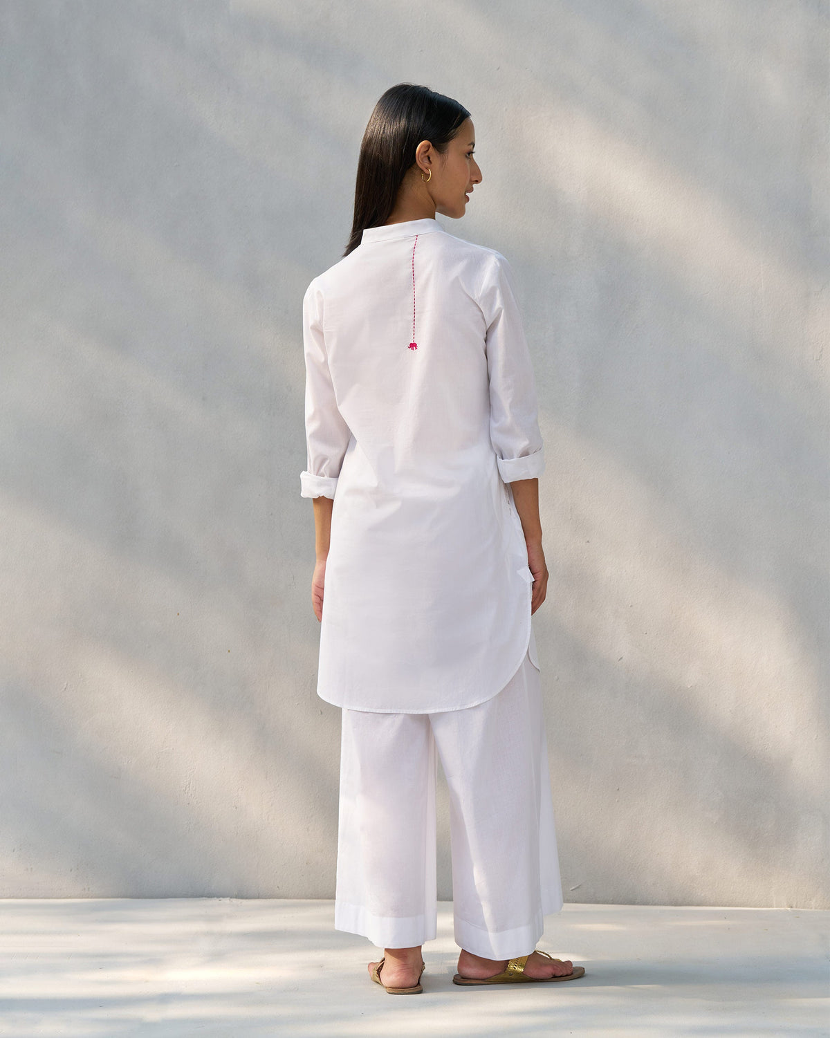 Back of a white Moon set tunic with a pink elephant embroidery.